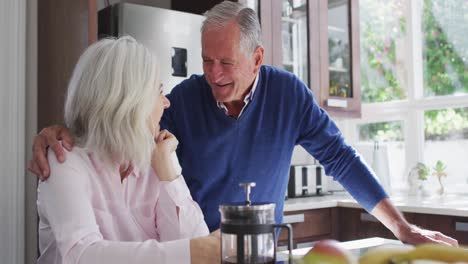 Happy-senior-couple-embracing-each-other-in-the-kitchen-at-home