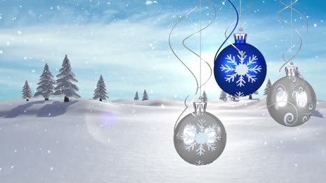 Animation-of-christmas-blue-and-silver-baubles-hanging-with-snow-falling-and-winter-landscape-on-blu