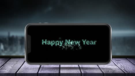 Animation-of-fireworks-exploding-and-happy-new-year-text-displayed-on-smartphone-screen-with-winter-