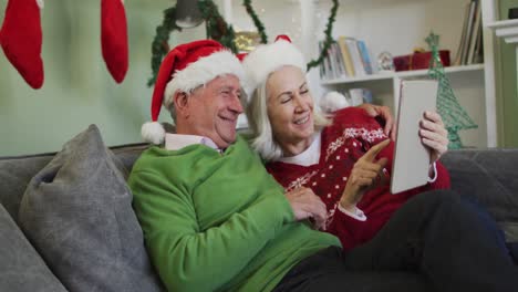 Happy-senior-caucasian-couple-celebrating-christmas-wearing-santa-hats