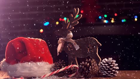 Animation-of-snow-falling-over-santa-hat-and-reindeer-christmas-decoration