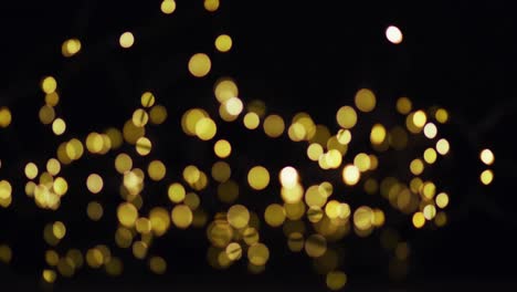 Multiple-gold-fairy-lights-glowing-on-black-background
