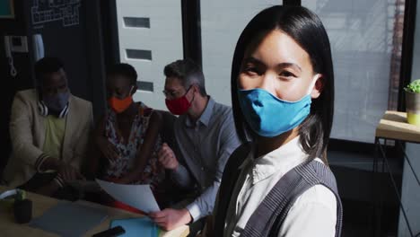 Portrait-of-asian-woman-wearing-face-mask-standing-at-modern-office