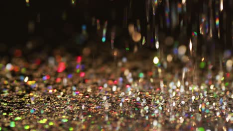 Multicoloured-glitter-gems-falling-on-black-background