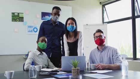 Portrait-of-office-colleagues-wearing-face-masks-in-meeting-room-at-modern-office