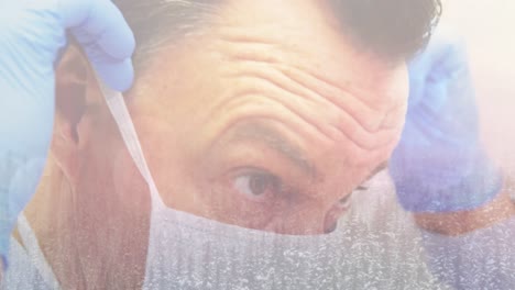 Animation-of-male-surgeon-putting-face-mask-on-over-winter-scenery-in-the-background
