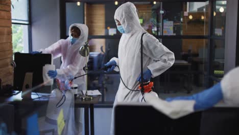 Team-of-health-worker-wearing-protective-clothes-cleaning-office-using-disinfectant-sprayer