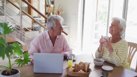 Senior-caucasian-couple-talking-to-each-other-having-breakfast-together-at-home