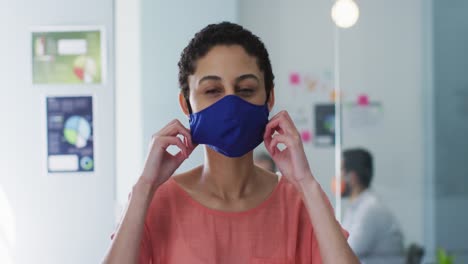 Portrait-of-caucasian-woman-adjusting-her-face-mask-at-modern-office