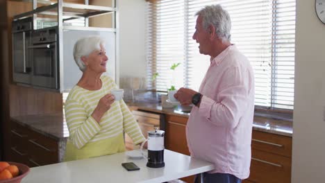 Älteres-Kaukasisches-Paar,-Das-Miteinander-Redet,-Während-Es-Zu-Hause-In-Der-Küche-Gemeinsam-Kaffee-Trinkt