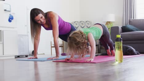 Caucasian-mother-and-daughter-practising-yoga-in-living-room
