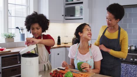 Mixed-race-lesbian-couple-and-daughter-preparing-food-in-kitchen