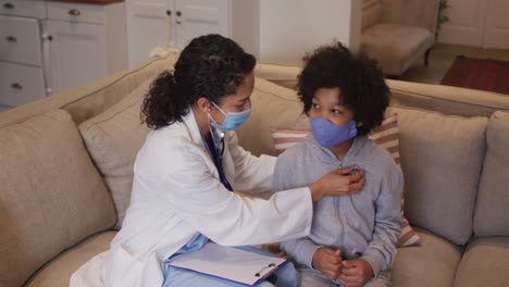 Mixed-race-female-doctor-wearing-mask-examining-mixed-race-girl-at-home
