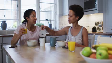 Mixed-race-lesbian-couple-preparing-and-eating-breakfast-in-kitchen