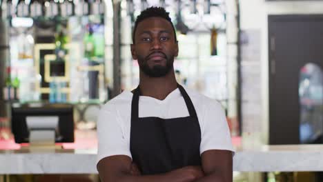 Portrait-of-african-american-barista-smiling-to-camera-wearing-apron-in-cafe