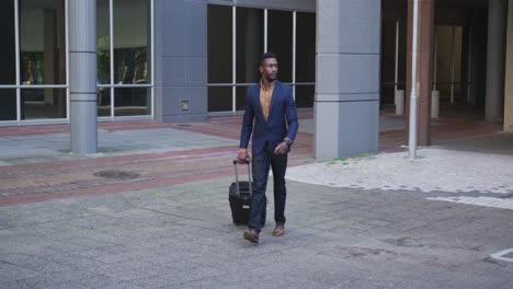 African-american-businessman-walking-with-suitcase-in-city-street