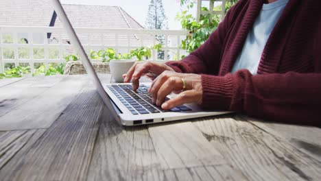 Midsection-of-senior-mixed-race-woman-using-laptop-outside