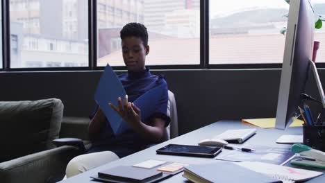 African-american-businesswoman-sitting-going-through-paperwork-in-modern-office