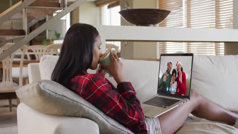 Mixed-race-woman-using-laptop-on-video-chat-with-family-during-christmas-at-home