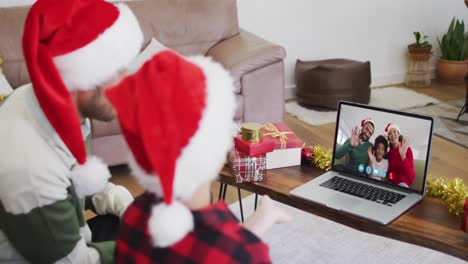 Kaukasischer-Vater-Und-Sohn-Tragen-Weihnachtsmützen-Auf-Laptop-Video-Chat-Während-Weihnachten-Zu-Hause