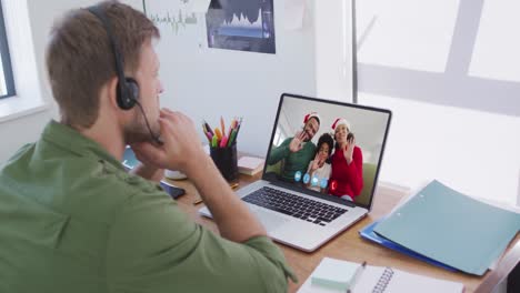 Caucasian-man-using-laptop-on-video-chat-with-family-during-christmas-at-home