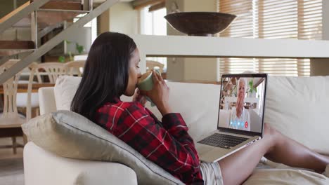 Mixed-race-woman-on-laptop-video-chat-having-coffee-at-home
