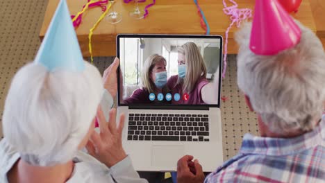 Kaukasisches-älteres-Paar-Auf-Laptop-Video-Chat-Mit-Partyhüten-Zu-Hause