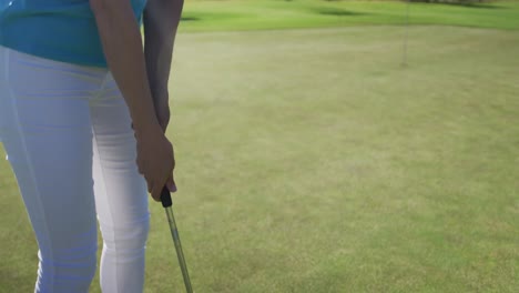 Caucasian-female-golf-player-taking-shot-from-bunker-standing-on-golf-field