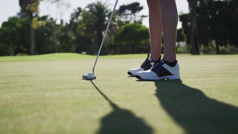 Caucasian-female-golf-player-taking-shot-from-bunker-standing-on-golf-field
