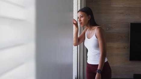 Mixed-race-woman-standing-and-looking-through-a-window