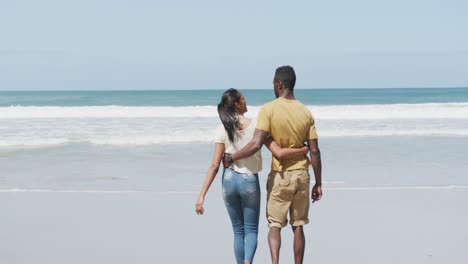 Rückansicht-Eines-Afroamerikanischen-Paares,-Das-Sich-Umarmt-Und-Am-Strand-Spazieren-Geht