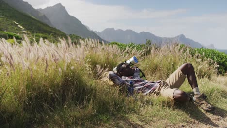 African-american-man-lying-on-a-rock-while-trekking-in-the-mountains