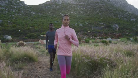 Diverse-fit-couple-exercising-running-across-a-field-in-the-countryside
