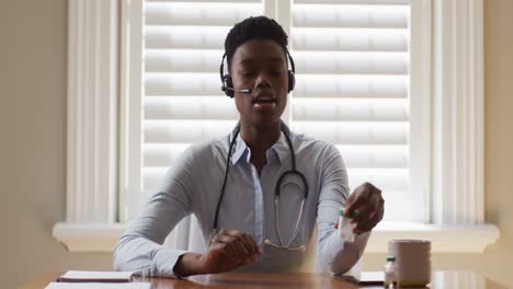 Portrait-of-african-american-female-doctor-wearing-phone-talking-while-looking-at-the-camera-at-home
