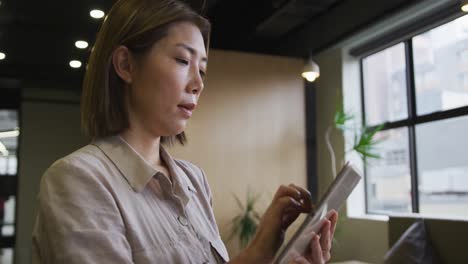 Mujer-De-Negocios-Asiática-De-Pie-Usando-Una-Tableta-Digital-En-Una-Oficina-Moderna