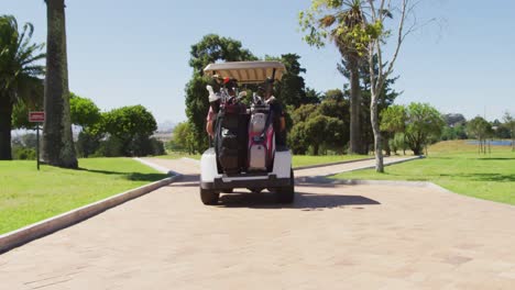 Rear-view-of-caucasian-senior-couple-driving-a-golf-cart-with-clubs-on-the-back-at-golf-course