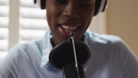 Afroamerikanische-Frau-Mit-Kopfhörern,-Die-Zu-Hause-Im-Mikrofon-Singt
