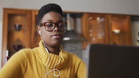 Afroamerikanische-Frau-Trägt-Kopfhörer-Und-Benutzt-Laptop,-Während-Sie-Von-Zu-Hause-Aus-Arbeitet