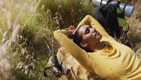 African-american-woman-lying-on-a-rock-while-trekking-in-the-mountains