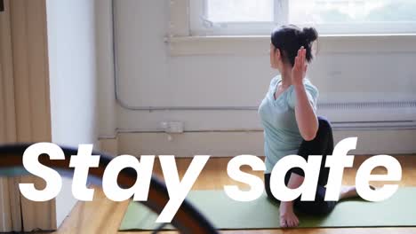 Animation-of-stay-safe-text-over-woman-practicing-yoga-at-home
