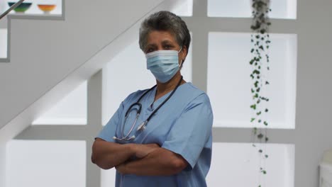 Portrait-of-senior-african-american-female-doctor-wearing-face-mask-looking-at-camera