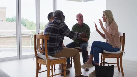 Two-diverse-senior-couples-sitting-in-circle-having-a-therapy-conversation-at-home