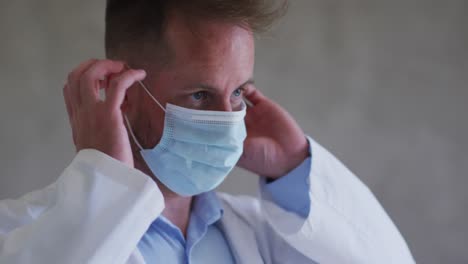 Caucasian-male-doctor-putting-on-a-face-mask