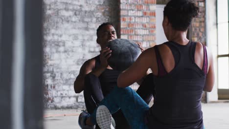 African-american-man-and-woman-exercising-with-medicine-ball-in-an-empty-urban-building