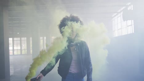 Mixed-race-woman-holding-green-flare-walking-through-empty-building