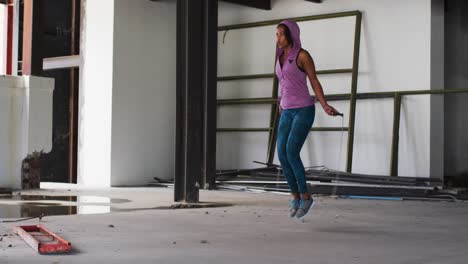 Mujer-Afroamericana-Con-Capucha-Saltando-Con-Cuerda-En-Un-Edificio-Urbano-Vacío