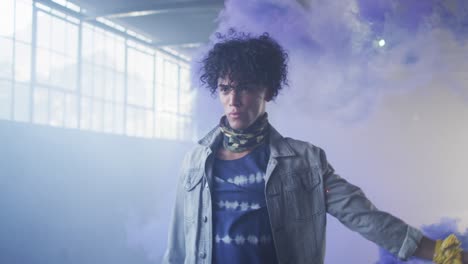 Mixed-race-man-holding-blue-flare-walking-through-empty-building