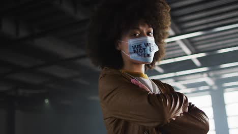Portrait-of-african-american-woman-wearing-protest-face-mask-in-empty-parking-garage