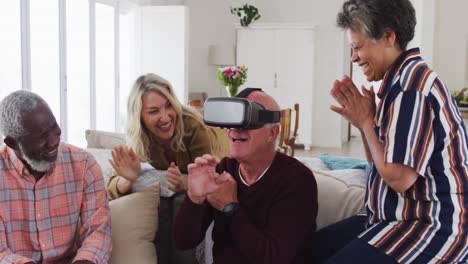 Two-diverse-senior-couples-sitting-on-a-couch-caucasian-man-is-using-vr-googles