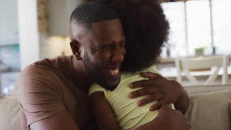 Hija-Afroamericana-Y-Su-Padre-Sonriendo-Y-Abrazándose-En-El-Sofá